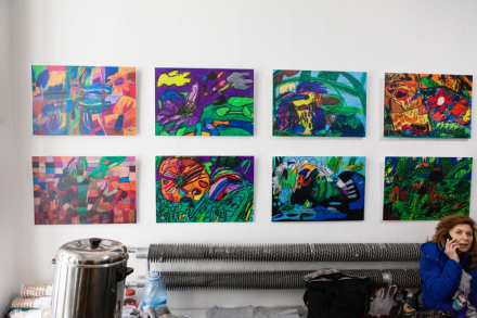 Kobieta siedzi na ławce w holu Warsztatów Kultury. Nad nią wiszą obrazy Igora Bryzka.