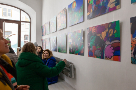 Na ścianie wiszą obrazy namalowane przez Igora Bryzka. Przyglądają się im ludzie.