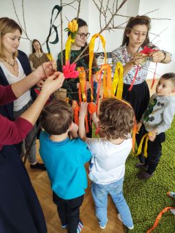 Dzieci i mamy ozdabiają gałąź wstążkami