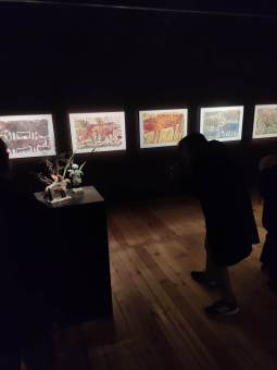 Chłopiec ogląda wystawę, obok stoi kolumna z figurkami.