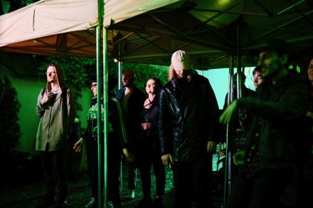 Publiczność stoi pod namiotem i słucha koncertu.