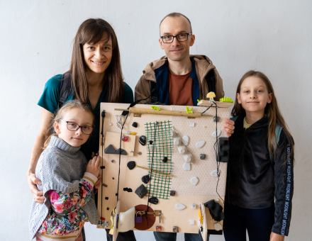 Rodzina z dwiema córkami prezentuje swoją ściankę sensoryczną,