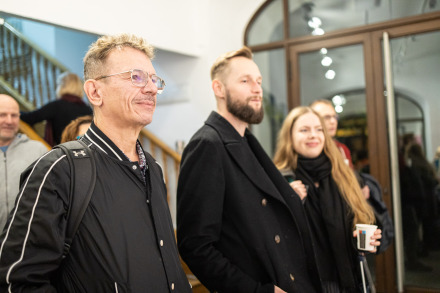 Zbliżenie na grupę ludzi z uwagą oglądających wystawę.