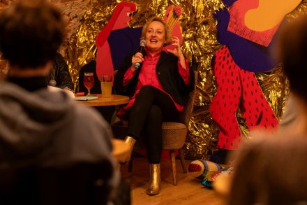 Autorka książki śmieje się do publiczności. W ręce trzyma mikrofon.