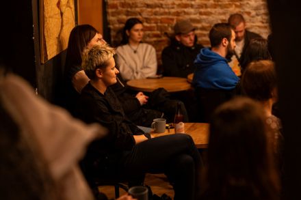 Ucczestnicy spotkania siedzą przy stolikach.