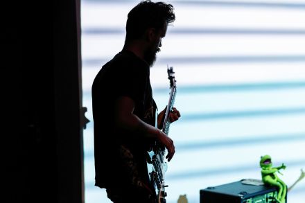 Mężczyzna widoczny jest z profilu. Gra na gitarze elektrycznej.