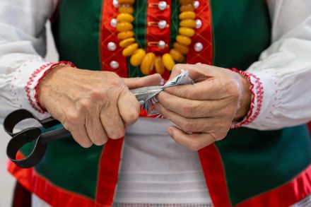 Ręce starszej pani, która nożycami wycina wycinankę.