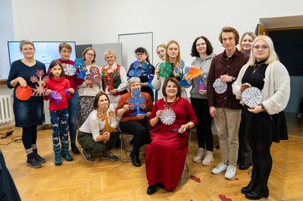 Zdjęcie uczestników warsztatu. Wszyscy trzymają wycinanki, które zrobili samodzielnie.