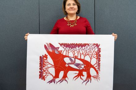 Kobieta pokazuje gotową wycinankę, która przedstawia wilka.
