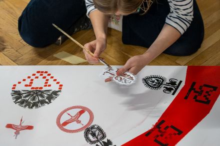 Kobieta maluje białą farbą gotową wycinankę.