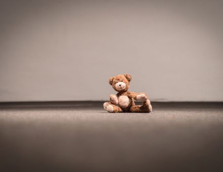 Na podłodze pod ścianą siedzi pluszak.