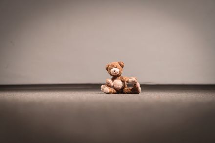 Na podłodze pod ścianą siedzi pluszak.