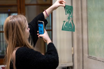 Dziewczyna trzyma w ręce wycinankę. Robi jej zdjęcie.