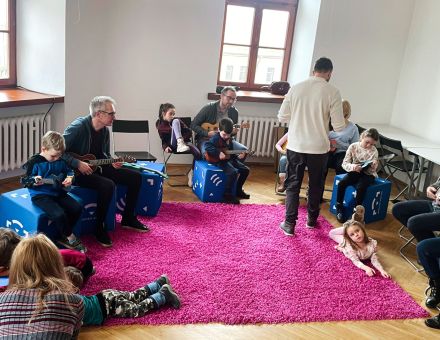 Uczestnicy warsztatów siedzą w kole i patrzą na prowadzącego.