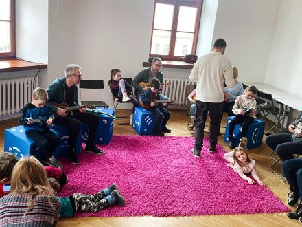 Uczestnicy warsztatów siedzą w kole i patrzą na prowadzącego.