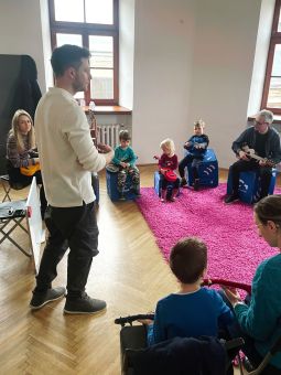 Prowadzący pokazuje, jak się gra na ukulele.