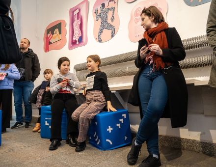 Dzieci siedzą na kubikach i jedzą zdrowe przysmaki. Przyglądają się też grafikom na ścianach. Dzieci siedzą na kubikach i jedzą zdrowe przysmaki. Przyglądają się też grafikom na ścianach.