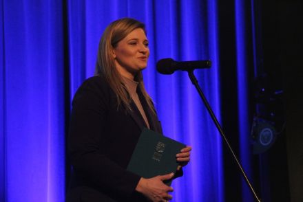 Prowadząca spotkanie przemawia na scenie.