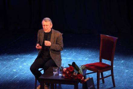 Riabczuk siedzi na krześle na scenie.