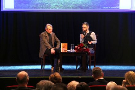 Pisarz siedzi przy stole z prowadzącym i rozmawiają.