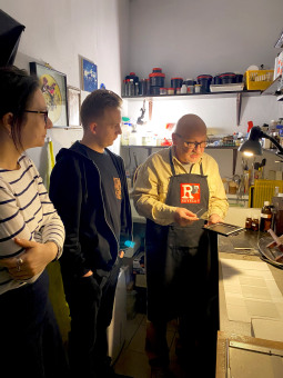 Kobieta i mężczyzna przyglądają się, jak fotograf trzyma w ręce płytki z aparatu. 