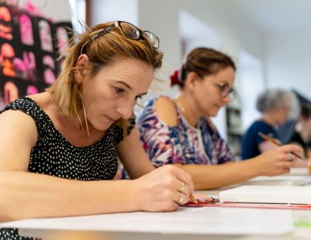 Dwie dziewczyny w skupieniu szkicują swoje obrazy.