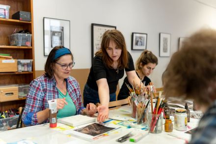 Prowadząca warsztaty rozkłada na stole obrazki do wzorowania się na nich.