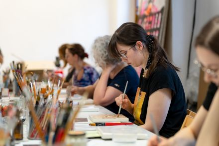 Uczestniczki warsztatów malują farbami.