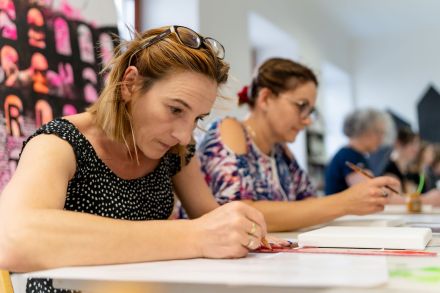 Dwie dziewczyny w skupieniu szkicują swoje obrazy.