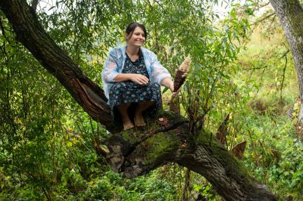 Kobieta siedzi na drzewie.