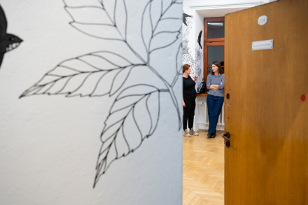 Otwarte drzwi prowadzą do sali wystawowej. Są w niej dwie kobiety.