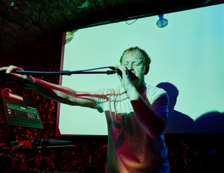 Wokalista trzyma w ręce statyw od mikrofonu.