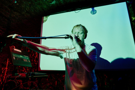 Wokalista trzyma w ręce statyw od mikrofonu.