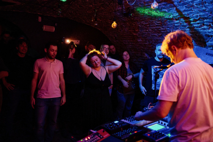 Mężczyzna obsługuje konsolę. Kobieta tańczy pod sceną.