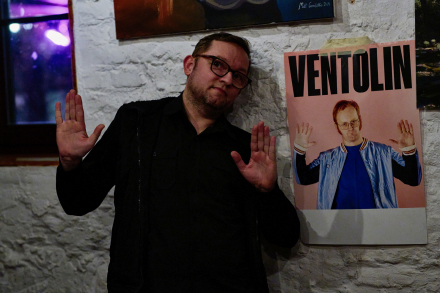 Mężczyzna stoi przy banerze reklamującym koncert Ventolina.