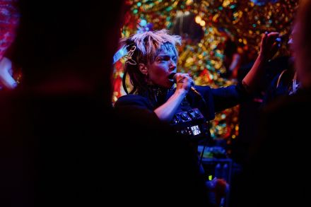 Zbliżenie na wokalistkę zza pleców słuchacza. 