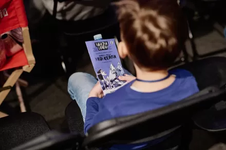 Chłopiec trzyma na kolanach gazetkę Magicznej Latarni.