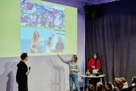 Kobieta wskazuje palcem na slajd prezentacji. Obok stoi mężczyzna. 