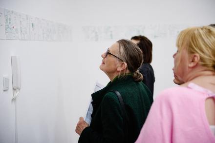 Dwie kobiety podziwiają obrazki na ścianie.