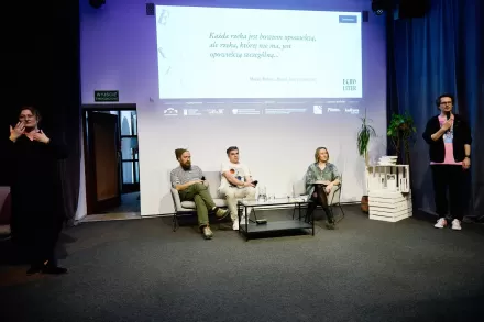 Nad głowami prelegentów jest wyświetlona prezentacja. 