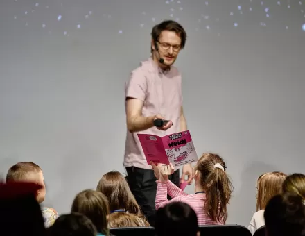 Mężczyzna kieruje mikrofon w stronę dzieci.