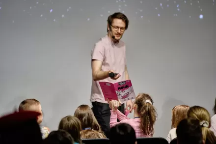 Mężczyzna kieruje mikrofon w stronę dzieci.