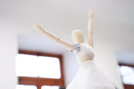 Drewniana baletnica ma rękę uniesioną do góry.