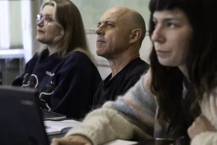 Twarze trzech uczestników wydarzenia, którzy siedzą przy stole.