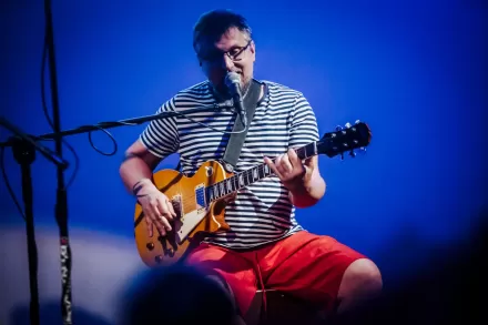 Mężczyzna śpiewa i gra na gitarze. 