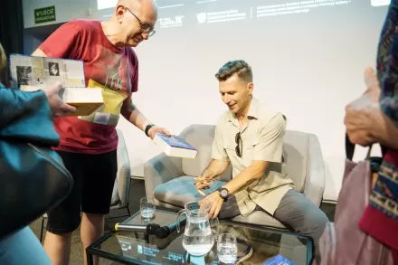 Gość spotkania podpisuje książki swoimi autografami. 