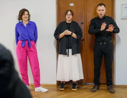 Przy ścianie stoi autorka wystawy, kuratorka wystawy oraz tłumacz PJM.