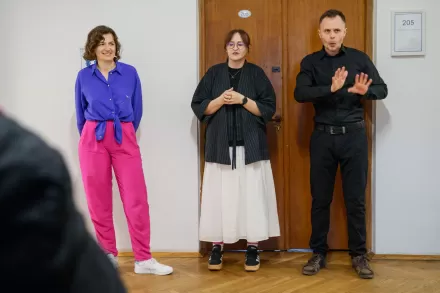 Przy ścianie stoi autorka wystawy, kuratorka wystawy oraz tłumacz PJM.