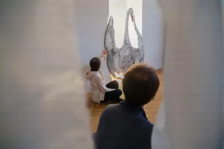 Dziewczynka wskazuje na łabędzia z mozaiki. Przygląda się temu kobieta. 