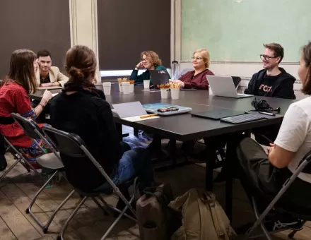 Uczestnicy i uczestniczki siedzą przy kwadratowym stole.